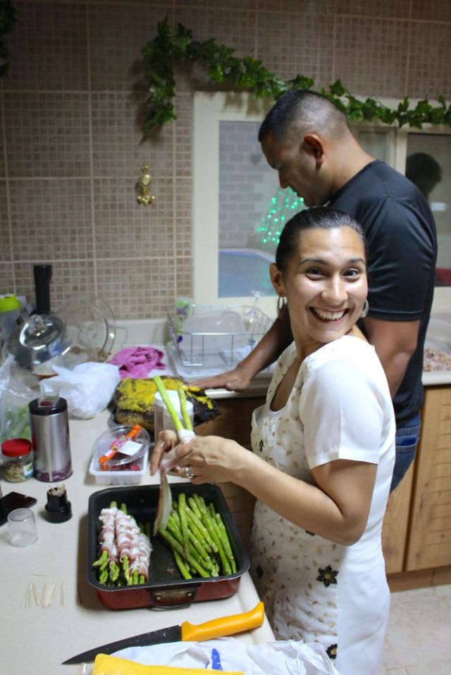 Christie wrapping asparagus in bacon and Sergio rubbing mustard on the camel