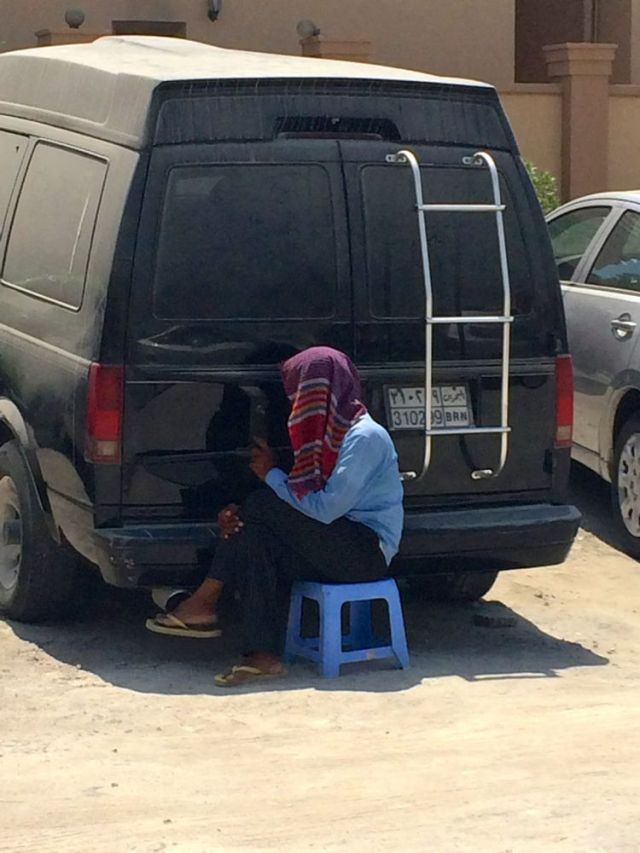 attendant creating dust art in the dirt lot while he waits